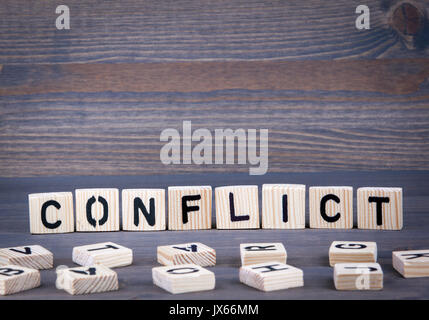 Konflikt Wort auf Holz Block geschrieben. Dunkles Holz Hintergrund mit Textur. Stockfoto