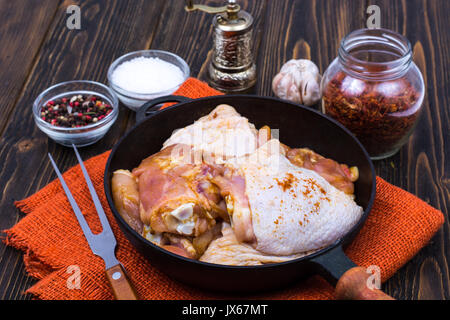 Gusseiserne Pfanne mit marinierten Hähnchen Schenkel Pfanne zum Braten. Studio Foto Stockfoto