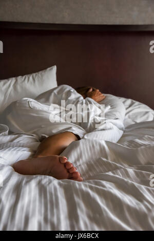 Frau im Bett über Kopf im Morgenlicht Stockfoto