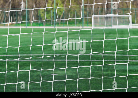 Hinter dem Ziel der Fußballplatz. Fußball-Fußball-net Hintergrund über grüne Gras oder Fußballplatz und verschwommen leeren Stadion. Fußball, Fußball Feld. Stockfoto