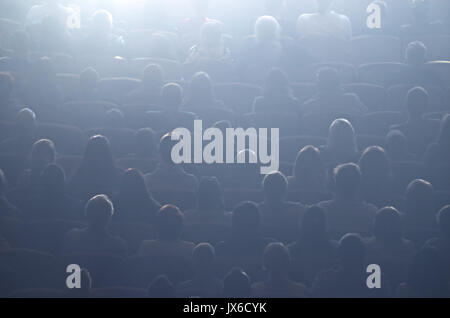 Kino oder Theater, Publikum in den Bildschirm Licht. Kino Halle mit Publikum. Kino Auditorium mit Menschen in den Stühlen aufzupassen Film. Die Zuhörer beobachten Stockfoto