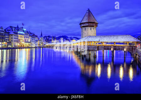 Altstadt von Luzern, Schweiz, mit hölzernen Kapellbrücke über die Reuss, der Wasserturm und der Promenade auf einem blauen winter Abend Stockfoto