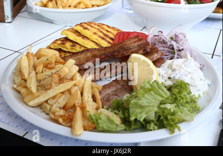 Traditionelle griechische Essen, Schnitzel mit Pommes frites Kartoffeln, Salat, Tzatziki Soße Zitrone und pita Brot in eine weiße Platte Stockfoto