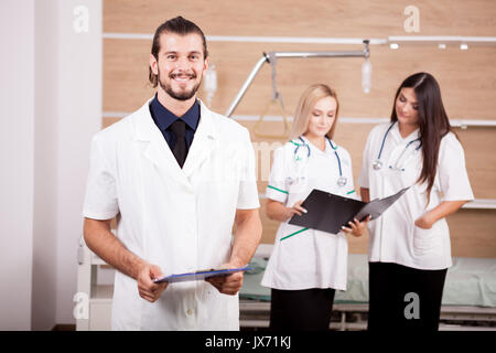 Portrait von zuversichtlich Arzt vor und Krankenschwestern in Zurück verschwommen Stockfoto