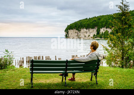 Frau ist entspannend auf einer Bank in Fayette State Park in der oberen Halbinsel, Michigan Stockfoto