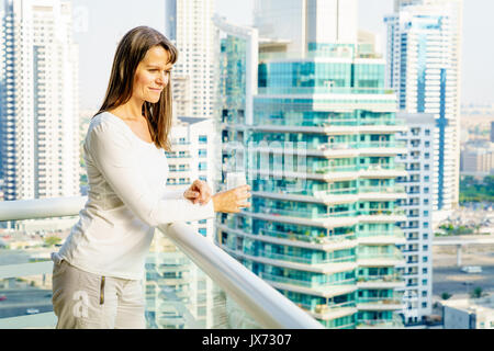 Reife Frau genießt die Stadt Blick von Ihrem Balkon in Hochhaus. Stockfoto