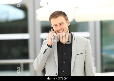 Vorderansicht Porträt einer jungen Geschäftsmann zu Fuß in Richtung Kamera und am Telefon sprechen Stockfoto