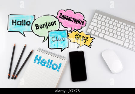 Hallo Wort Wolke in verschiedenen Sprachen der Welt, Hintergrund Konzept. Büro Schreibtisch Tisch mit Computer, Smartphone und Notebook. Stockfoto