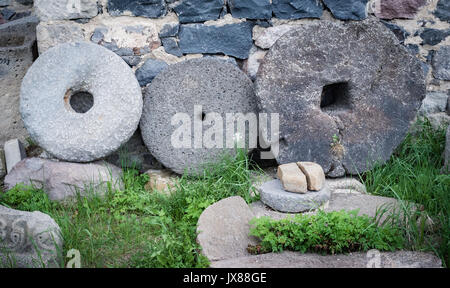 Stein Granit Räder mit rostigem Metall rim auf grünem Gras in der Nähe der Wand isoliert. Stockfoto