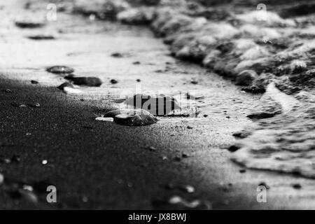 Ein in der Nähe der Lake Shore, mit Einzelheiten zu Luftblasen im Wasser und kleine Steine und Kiesel auf dem Sand Stockfoto