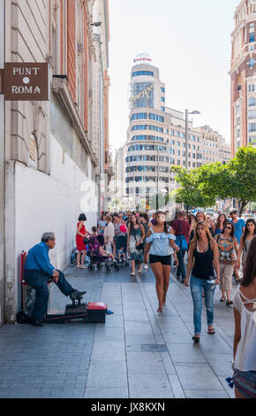 Limpiabotas en la Gran Vía de Madrid con El edificio Capitol al Fondo. España Stockfoto