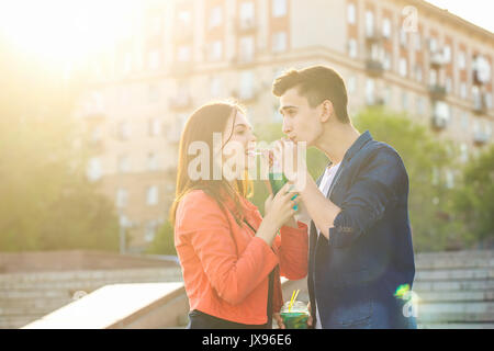 Jugendliche trinken Obst frisch von der Brille. Sie trinken aus einem Glas. Ein Paar in Liebe auf ein Datum. Romantik der ersten Liebe. Stockfoto