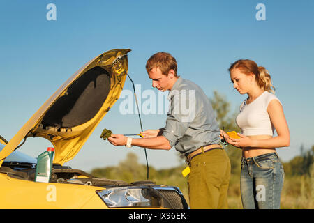 Paar in der Liebe. Road Trip. Der Kerl, der Kontrolle des Ölstands. Das Mädchen schaut auf das, was er tut. Stockfoto