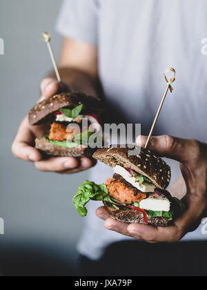 Junge hipster Holding vegetarische Karotte Tofu Burger. Detailansicht, selektiver Fokus Stockfoto