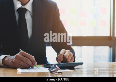in der Nähe Konten, Business Mann oder Rechtsanwalt Steuerberater arbeiten auf Verwendung eines Taschenrechners und schreiben auf Dokumente Stockfoto