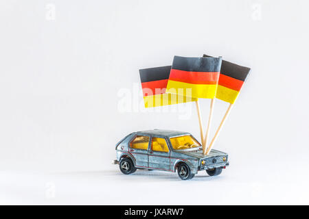 Modellauto. Ein spielzeugauto der Marke Volkswagen VW Golf, leicht demoliert. Mit Deutschlandflagge, Made in Germany. Stockfoto