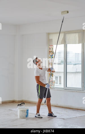 Ethnische Arbeiter Malerei Mauern in einer Halle mit Walze, die Kamera auf glidecam bewegen Stockfoto