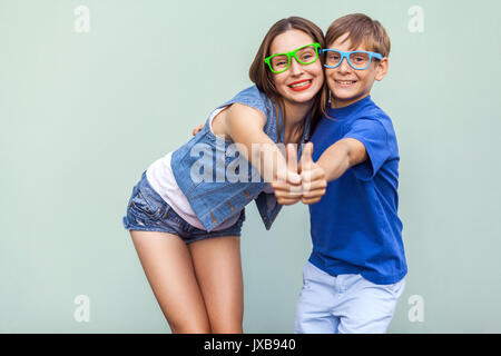 Familie, Emotionen und Gefühle. Ältere Schwester und ihrem Bruder mit Sommersprossen, über blauen Hintergrund zusammen stellen, von der Kamera suchen mit toothy Lächeln Stockfoto