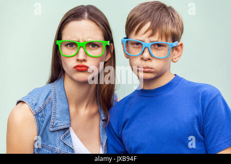 Familie, schlechte Emotionen und Gefühle. Ältere Schwester und ihrem Bruder mit Sommersprossen, über hellblauen Hintergrund zusammen stellen, von der Kamera suchen mit Unha Stockfoto