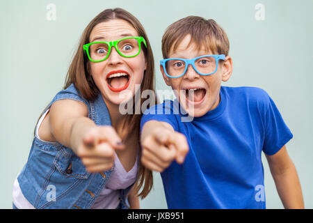 Gute Emotionen und Gefühle. Ältere Schwester und ihrem Bruder mit Sommersprossen, über hellblauen Hintergrund zusammen stellen, von der Kamera suchen mit Fi Stockfoto