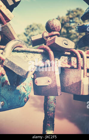 Retro stilisierte Bild der alten verrosteten Vorhängeschlössern auf einer Brücke, liebe Symbol, geringe Tiefenschärfe. Stockfoto