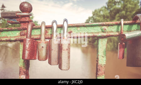 Retro stilisierte Bild der alten verrosteten Vorhängeschlössern auf einer Brücke, liebe Symbol, geringe Tiefenschärfe. Stockfoto