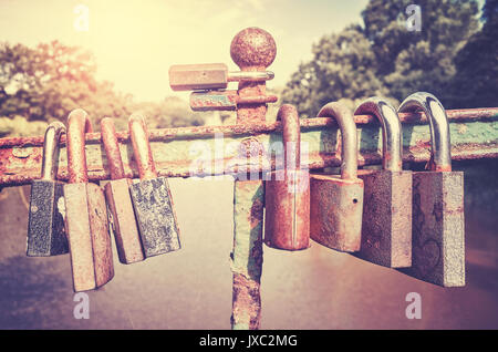 Retro stilisierte Bild der alten verrosteten Vorhängeschlössern auf einer Brücke, liebe Symbol, geringe Tiefenschärfe. Stockfoto