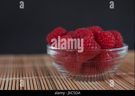 Horizontale gedreht, Weg - mit einer Kopie von einer Schale frisch gepflückte Himbeeren auf einer Bambus matte und mit dunklem Hintergrund zentriert Stockfoto
