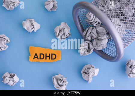 ADHD (Attention Deficit hyperactivity Disorder). Grau zerknittertes Papier Kugeln rollen aus einem Mülleimer. Close Up. Konzept Bild. Stockfoto