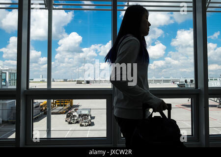 Die Passagiere durch ein Fenster mit Blick auf die Rollbahn am Flughafen München auf dem Weg zu den Abflug-Gates, Bayern, Deutschland Stockfoto