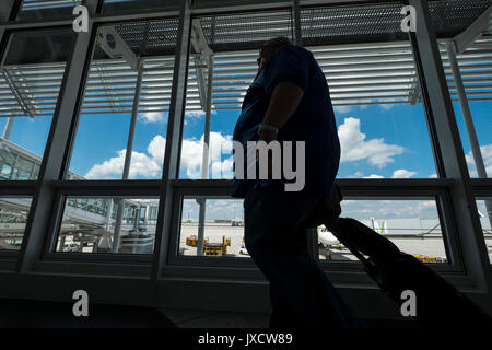 Die Passagiere durch ein Fenster mit Blick auf die Rollbahn am Flughafen München auf dem Weg zu den Abflug-Gates, Bayern, Deutschland Stockfoto