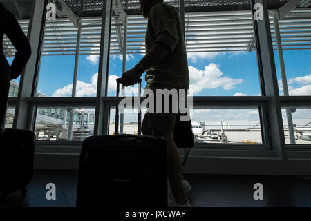 Die Passagiere durch ein Fenster mit Blick auf die Rollbahn am Flughafen München auf dem Weg zu den Abflug-Gates, Bayern, Deutschland Stockfoto