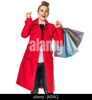 Im Herbst helle Halten. Volle Länge Portrait von lächelnden stilvolle Frau im roten Mantel auf Weiß mit Tüten snapping Finger isoliert Stockfoto