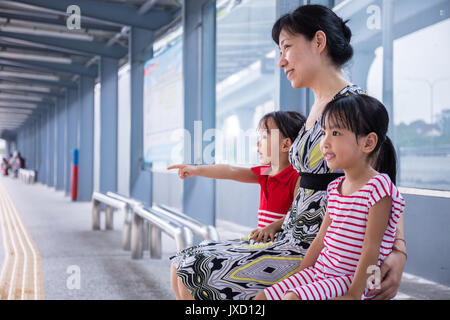 Asiatische chinesische Mutter und Töchter warten auf einen Bus an der Haltestelle Stockfoto