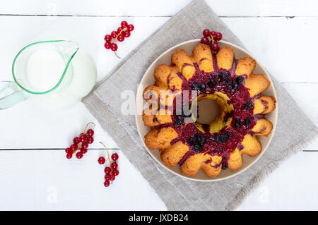 Frisch gebackene Kuchen mit Sommer Beeren, Kanne Milch auf einem weißen Hintergrund. Ansicht von oben. Stockfoto