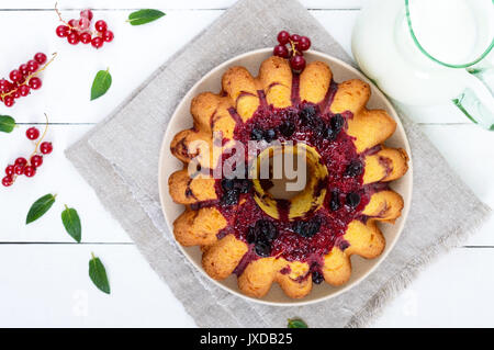Frisch gebackene Kuchen mit Sommer Beeren, Kanne Milch auf einem weißen Hintergrund. Ansicht von oben. Stockfoto