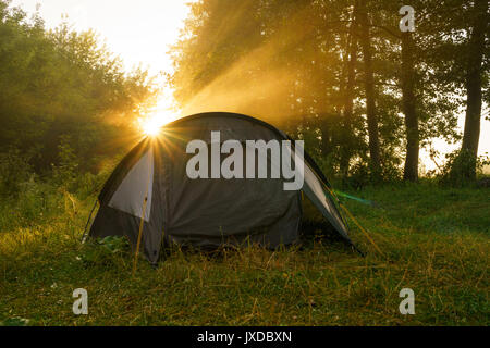 Camping Zelten am ufer bei Sonnenaufgang. Touristen im Wald Stockfoto