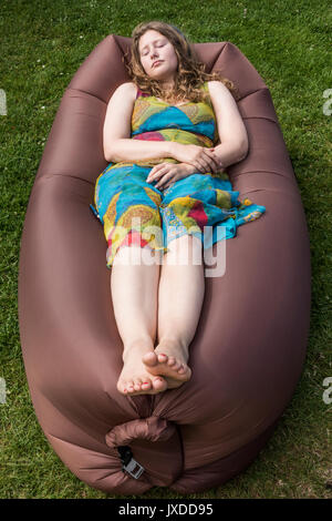 Eine hübsche junge Frau schlafend in einem aufblasbaren liege auf einem Campingplatz. Stockfoto