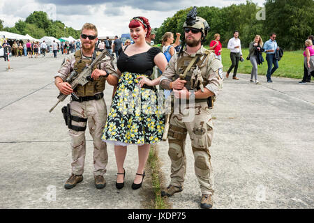 Re-enactors gekleidet, wie moderne Soldaten im 21. Jahrhundert militärische Uniformen posiert mit Frau im Kleid der 40er Jahre während der militaria Messe Stockfoto