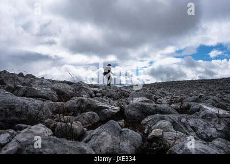 Berg Walker in Silhouette gegen bewölkter Himmel auf Rock Bereich bis zur oberen Cairn von Munro in den schottischen Highlands Stockfoto