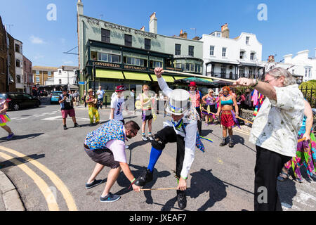 Allsorts Morris Männer und Frauen tanzen im hellen Sonnenschein an der Promenade während der broadstairs Folk Woche. Allsorts aus verschiedenen Morris Dance Teams, also Kostüme abwechslungsreich. Stockfoto