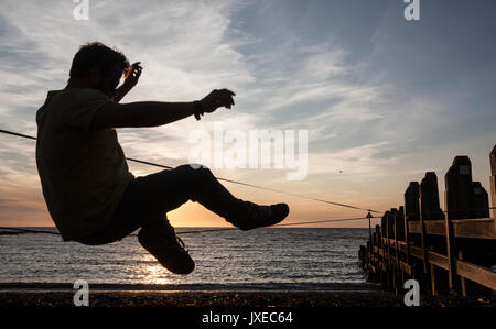 Ceredigon, Aberystwyth, Großbritannien. 15 Aug, 2017. UK Wetter: Aberystwyth Studenten von slack-line Club auf der Slackline an Aberystwyth Strand bei Sonnenuntergang, Cardigan Bay, Ceredigion, Wales, Großbritannien, am Ende eines sonnigen Tag in diesem Badeort in der Mitte von Wales. Credit: Paul Quayle/Alamy leben Nachrichten Stockfoto