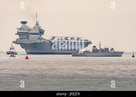 Portsmouth, Großbritannien. 16 Aug, 2017. Der Träger HMS Queen Elizabeth Türme über HMS Hurworth Credit: Vernon Nash/Alamy leben Nachrichten Stockfoto