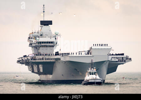 Portsmouth, Großbritannien. 16 Aug, 2017. Schlepper, die HMS Queen Elizabeth in Portsmouth Harbour mit ihrem Hubschrauber escort oben Credit: Vernon Nash/Alamy leben Nachrichten Stockfoto