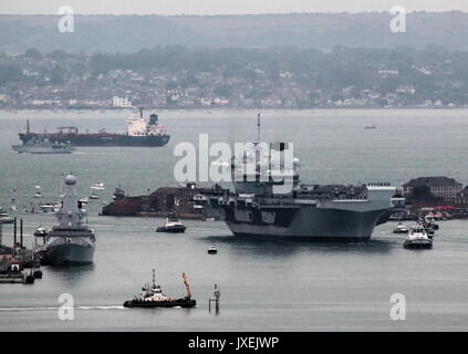 Portsmouth, Großbritannien. 16 August, 2017. - Der größte Kriegsschiff der Royal Navy Segel in Home port-HMS Queen Elizabeth, die erste von zwei 65.000 Tonnen, 900 m lang, state-of-the-art Flugzeugträger segelte in Portsmouth Naval Base in den frühen Stunden des Morgens sanft drückte und drängte durch sechs Schleppern in ihre neuen Liegeplatz auf der Princess Royal Jetty. Die £3 Mrd. ffr, das größte Kriegsschiff, das jemals für die Royal Navy gebaut, kam in ihrem Heimathafen zwei Tage vor dem ursprünglichen Zeitplan. Foto: Steve Foulkes/Ajax/Alamy Leben Nachrichten. Stockfoto