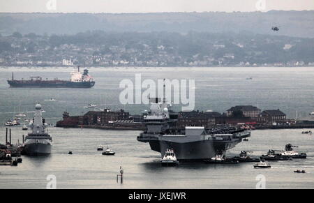 Portsmouth, Großbritannien. 16 August, 2017. - Der größte Kriegsschiff der Royal Navy Segel in Home port-HMS Queen Elizabeth, die erste von zwei 65.000 Tonnen, 900 m lang, state-of-the-art Flugzeugträger segelte in Portsmouth Naval Base in den frühen Stunden des Morgens sanft drückte und drängte durch sechs Schleppern in ihre neuen Liegeplatz auf der Princess Royal Jetty. Die £3 Mrd. ffr, das größte Kriegsschiff, das jemals für die Royal Navy gebaut, kam in ihrem Heimathafen zwei Tage vor dem ursprünglichen Zeitplan. Foto: Steve Foulkes/Ajax/Alamy Leben Nachrichten. Stockfoto