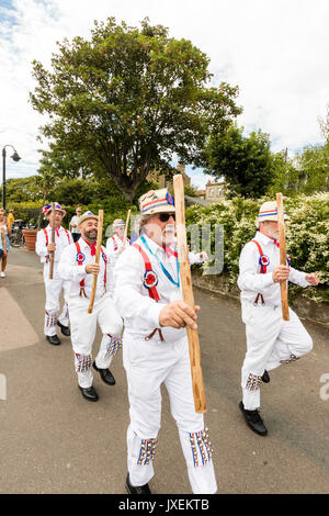 Traditionelle englische Morris Men von Hartley Morris Dancers an der Strandpromenade an der jährlichen Broadstairs Folk Woche. Tanzen in zwei Reihen tragen weiße Hosen und Hemden mit Stroh Hüte, holding Holzpfähle. Stockfoto