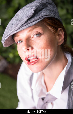 Junge rothaarige Frau, die als Mann verkleidet in den Garten Stockfoto
