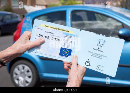 Woman's Hände halten ein Blue Badge Parkscheibe in Großbritannien für behinderte Fahrer. Stockfoto