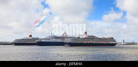 Die drei Königinnen, Elizabeth, Victoria und Mary, die auf dem Fluss Mersey abgebildet sind, werden von den Roten Pfeilen gegrüßt, um Cunards 175-jähriges Jubiläum zu feiern. Stockfoto